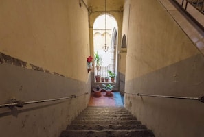 Eine enge Treppe mit Handlauf, die zu einem rundbogigen Durchgang führt.