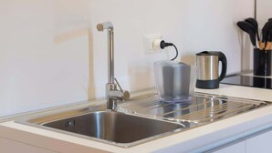A kitchen with a stainless steel sink, a kettle, and a coffee maker on the counter. - Appartamento spazioso Napoli centro con terrazzo (Naples)