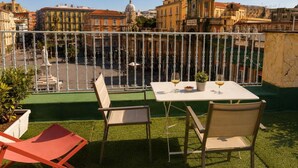 Una terraza al aire libre con mesa y sillas, vista del paisaje urbano y una barandilla.