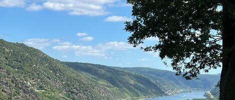 A river with boats, surrounded by hills and greenery.