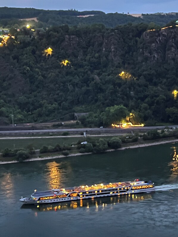 Une rivière avec un bateau, un pont et une colline boisée.