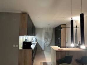 Eine moderne Küche mit einer Holzausziehtheke, einer Kaffeemaschine und einem Einbauofen.