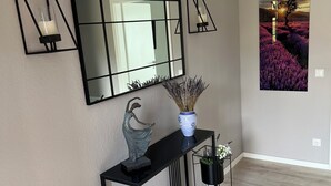 A modern interior with a console table, a large mirror, and two wall-mounted sconces.