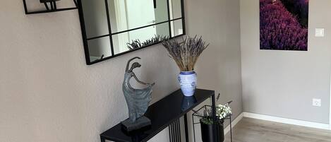 Un interior moderno con una consola, un espejo grande y dos apliques de pared.