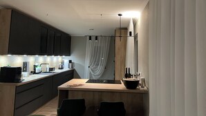A modern kitchen with dark cabinets, a wooden countertop, and a dining area with two chairs.