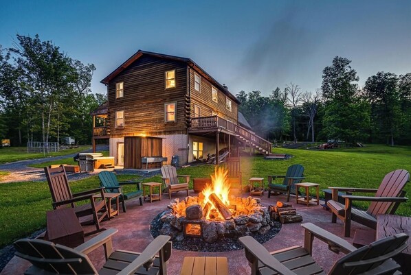 Une cabane en rondins avec un foyer et des sièges d’extérieur.