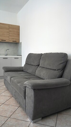 Un sofá gris con un mueble de madera encima.