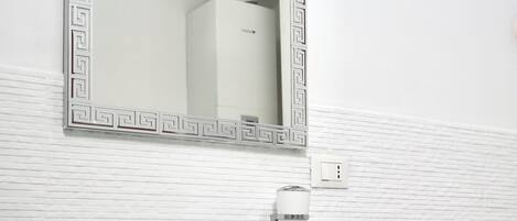 Un baño con un tocador blanco, un espejo con marco decorativo, un perchero y una bañera.