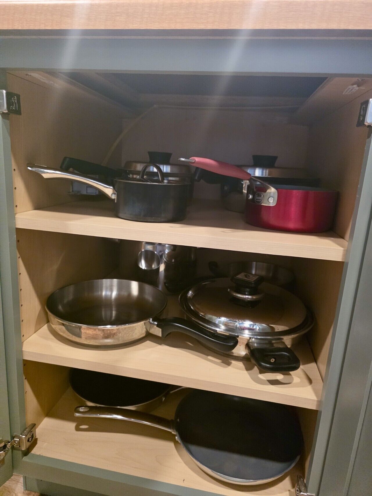 Un meuble de cuisine doté de plusieurs étagères où sont rangés divers ustensiles de cuisine.