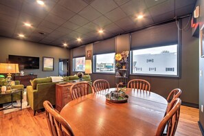Ein modernes Wohnzimmer mit Esstisch, grünem Sofa und Fernseher.