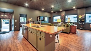 A modern kitchen with a central island, a dining area with a sofa, and a view of the outside.