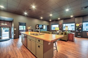 Cozinha moderna com ilha central, área de refeições com sofá e vista para o exterior.