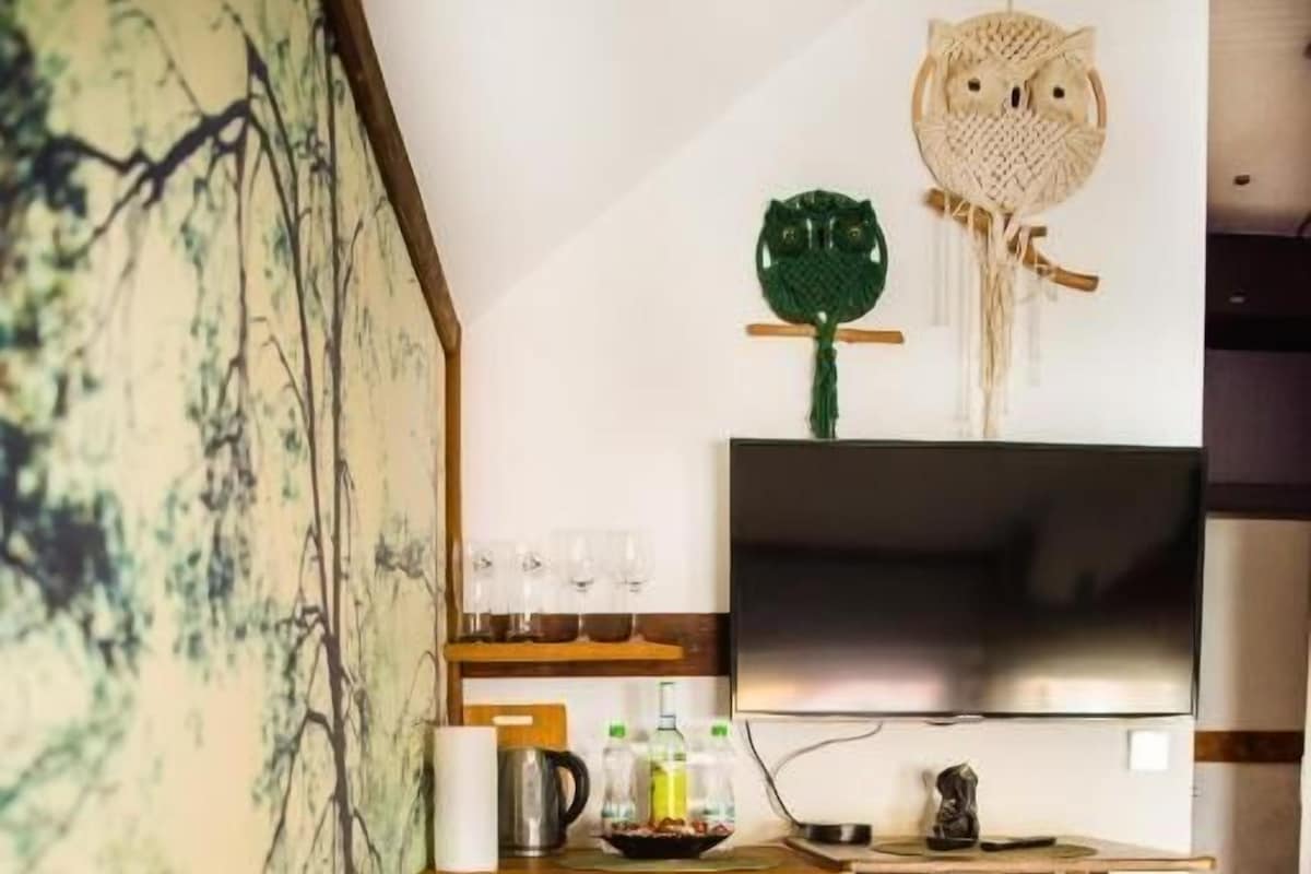 A compact room with a bed, a wooden cabinet, a small table, and a television.