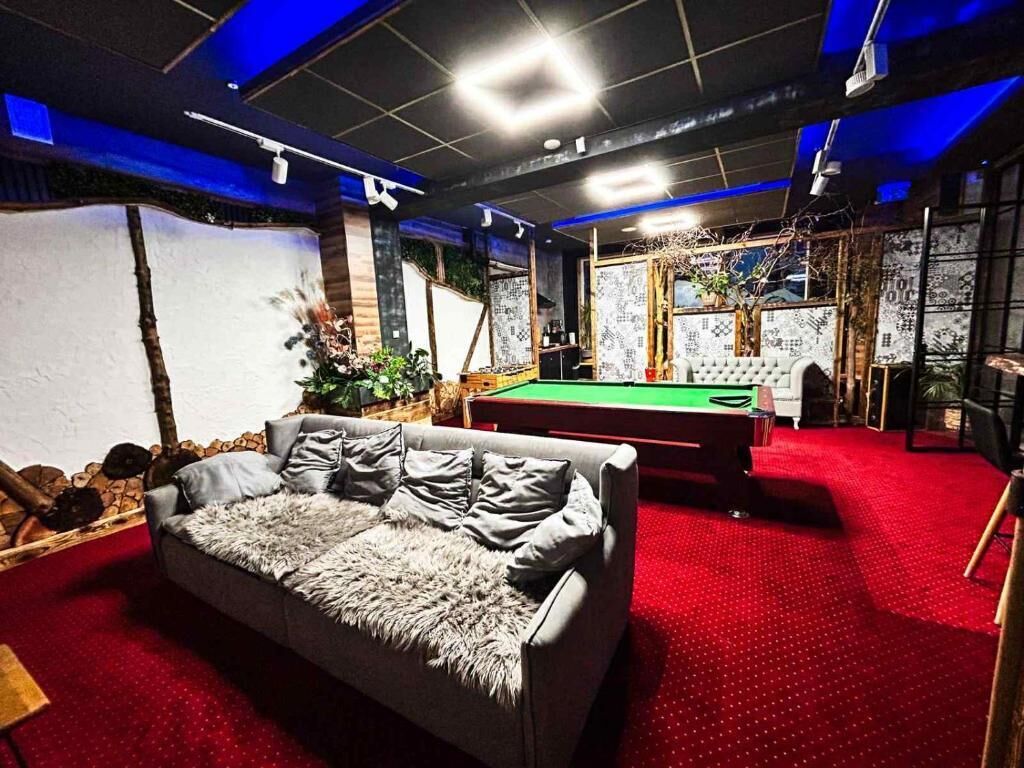 Una habitación con mesa de billar, sofá y alfombra roja.