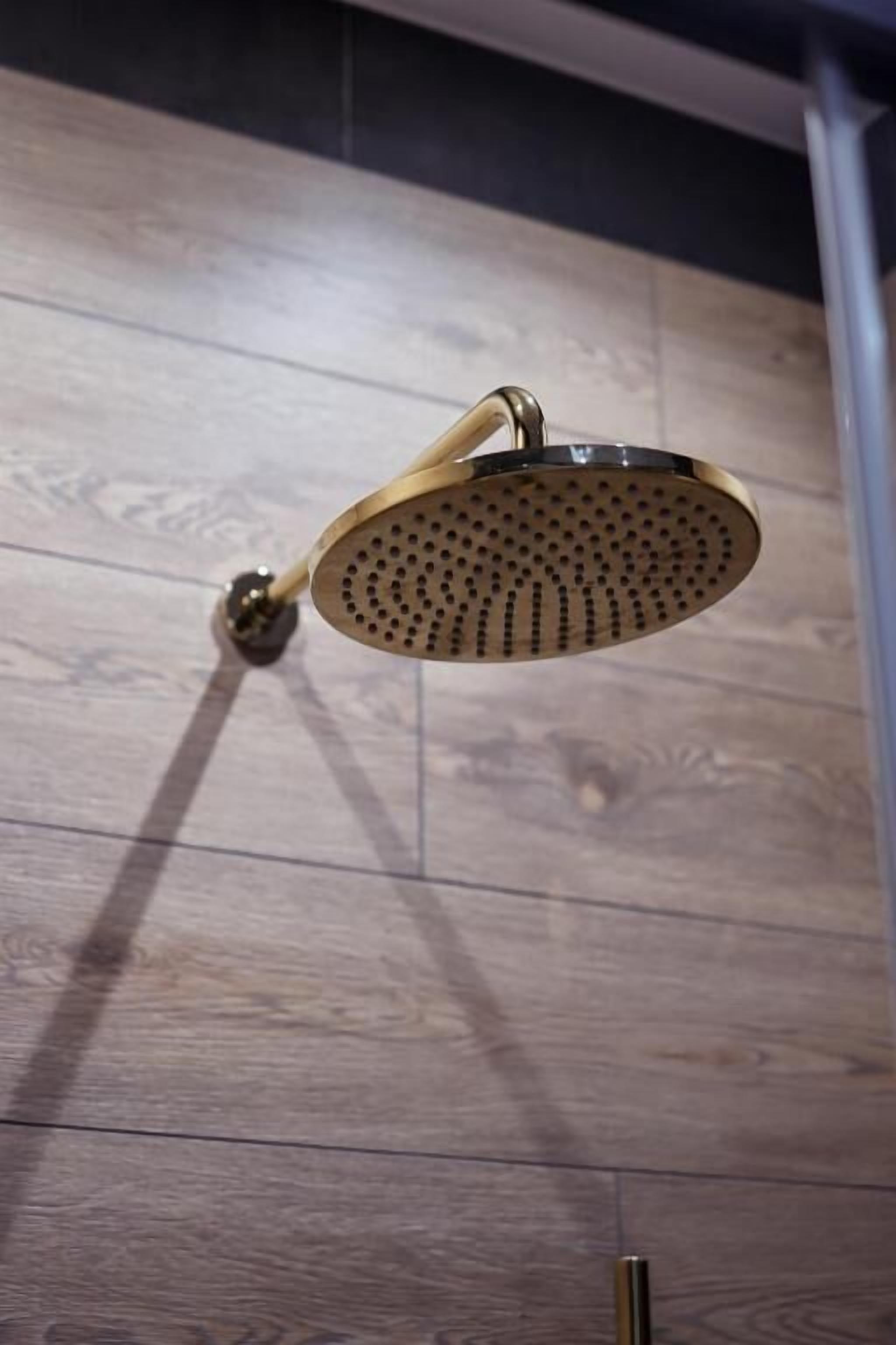 A showerhead with a curved design, mounted on a wall with a wooden panel.