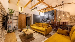 Un salon comprenant un canapé, une table basse et un coin repas délimité par une clôture en bois.