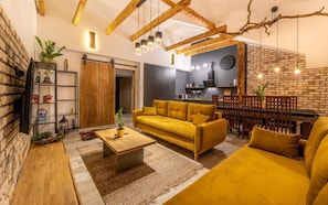 A living room with a sofa, coffee table, and a dining area with a wooden fence.