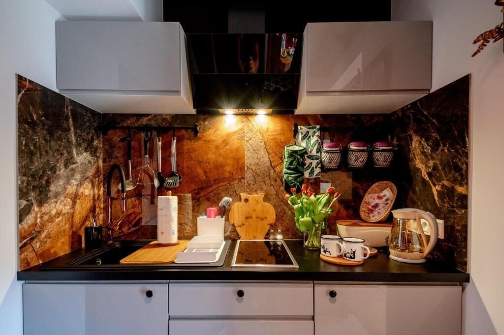A kitchen with a marble backsplash, a sink, a coffee maker, and a decorative cat cutout.