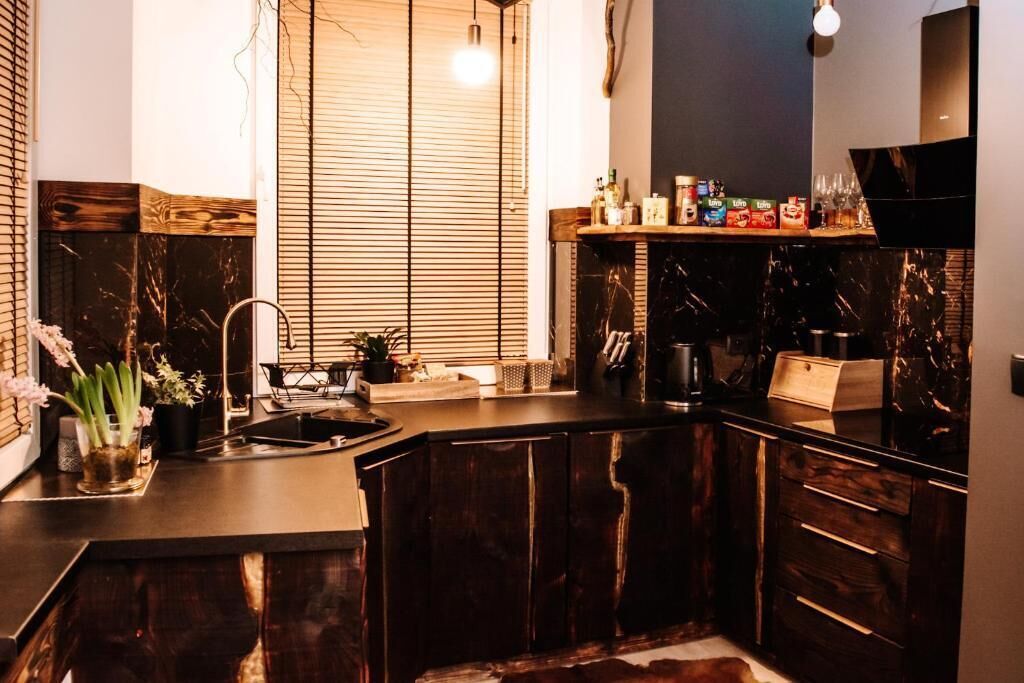 Una cocina moderna con armarios de madera oscura, encimera de mármol negro y ventana con persianas.