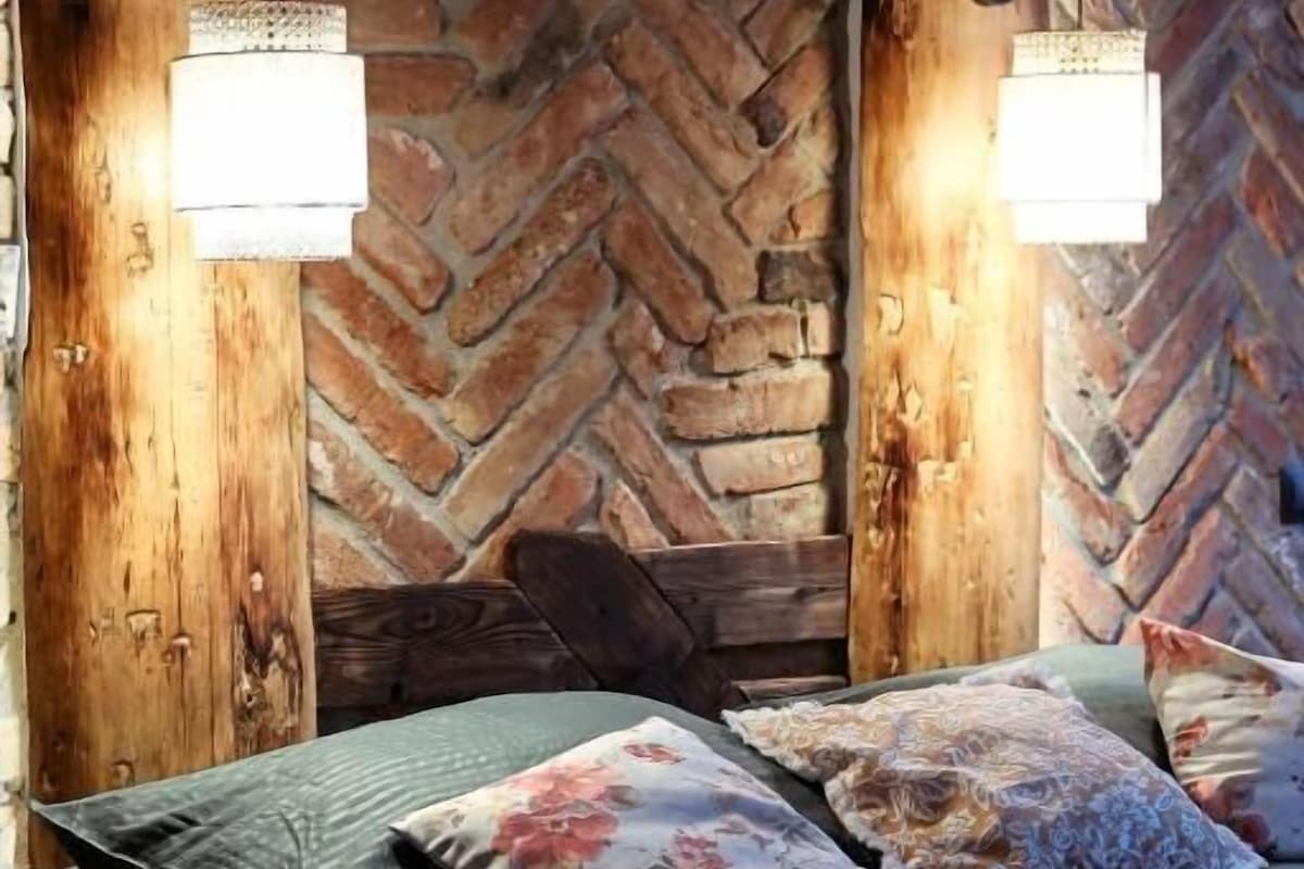A bed with a herringbone-patterned wall behind it, two wall-mounted light fixtures, and a cat on the bed.