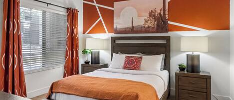 Une chambre moderne avec un lit, deux tables de chevet, une commode, une fenêtre avec des stores et un mur orné d’un motif géométrique et d’un tableau.