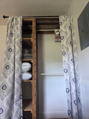 Une pièce dotée d’une armoire intégrée, d’une étagère en bois et d’un mur blanc.