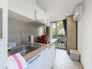 Eine kompakte Küche mit Spüle, Herd und Schränken, die auf einen Balkon mit Blick führt.