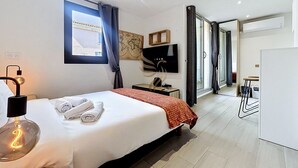 Een moderne hotelkamer met een bed, bureau, flatscreen televisie, een wereldkaart aan de muur en uitzicht op de aangrenzende kamer.