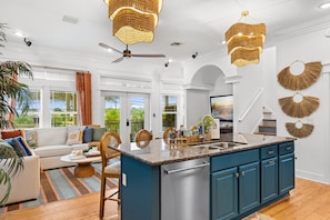 A spacious living room with a large island kitchen, ceiling fans, and decorative wall art. - Pool • 1-Min Beach Walk • Game Room • Sleeps 14 (Panama City)