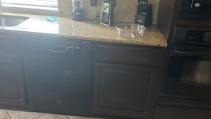 A kitchen with dark cabinetry, a countertop, a sink, a coffee maker, a toaster, and a microwave. - Spacious 5-bedroom house in enchanting Austin with AC (Austin)