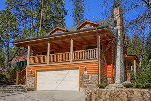 A log cabin with a balcony, a garage, and a stone foundation. - Reel Therapy Lodge -formerly Semper Fi with dock (Bass Lake)