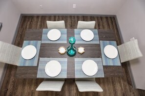 A dining table with four chairs, a central decorative item, and placemats. - Modern Spacious Home in Quiet Neighborhood (La Porte)