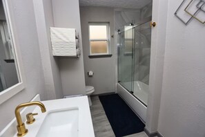 A bathroom with a white sink, a glass shower enclosure, a toilet, and a towel rack. - Modern Spacious Home in Quiet Neighborhood (La Porte)