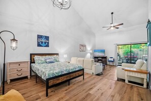 Ein Schlafzimmer mit Bett, Schreibtisch, Stuhl, Fernseher und einem Balkon mit Blick.