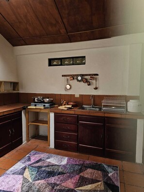 A kitchen with wooden cabinets, a stove, a sink, and a hanging pot rack.