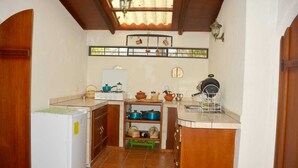 A compact kitchen with a refrigerator, stove, and various cooking utensils. - Arco Iris Farm surrounded by mountains and nature in the Sacred Valley Vilcabamba (Vilcabamba)
