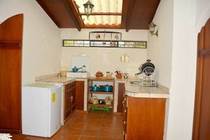 A compact kitchen with a refrigerator, stove, and various cooking utensils.