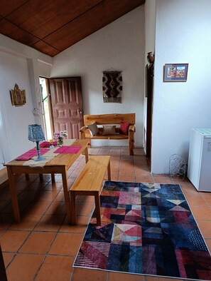 A room with a wooden bench, a table, a patterned rug, and a door.