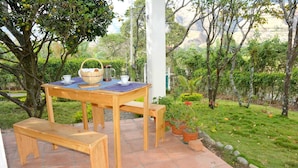 An outdoor wooden table with benches, a basket, and a cup, set on a tiled patio surrounded by greenery. - Arco Iris Farm surrounded by mountains and nature in the Sacred Valley Vilcabamba (Vilcabamba)