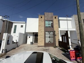 A modern building with a central entrance, a gated driveway, and a visible signboard. - Mini loft junto a la UDEM (San Pedro Garza García)