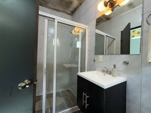 A bathroom with a glass shower enclosure, a white sink, and a mirror. - Mini loft junto a la UDEM (San Pedro Garza García)