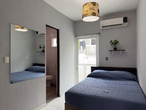 Een slaapkamer met een bed, een spiegel, een airconditioner en een raam.