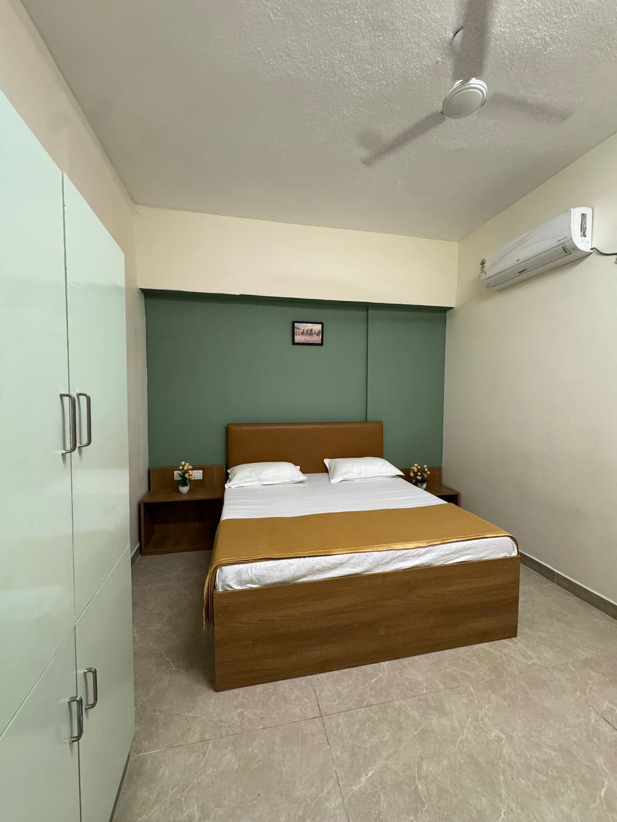 Een slaapkamer met een bed, nachtkastje, kledingkast en airconditioning.