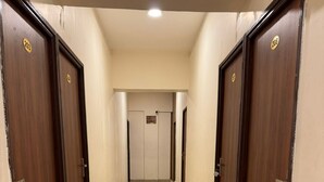 A corridor with wooden doors, each marked with a number. - Laya Crest (Chennai)