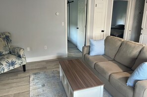Ein Wohnzimmer mit einer Couch, einem gemusterten Sessel und einem Holztisch.