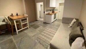 Ett kompakt bostadsutrymme med en matplats, ett litet kök och en soffa.