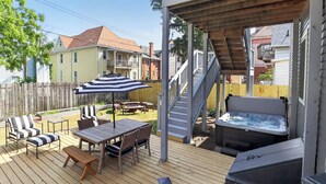 En terrasse med udendørs møbler, et spabad og en trappe til en anden terrasse.