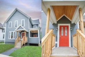 A two-story house with a front porch, a red door, and a wooden staircase. - 4BR Family Retreat | Private Hot Tub + 2 Kitchens (Michigan City)