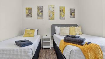Habitación de hotel con dos camas, una mesita de noche pequeña y cuatro obras de arte colgadas en la pared.