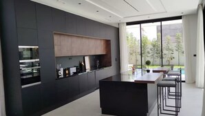 Una cocina moderna con una isla central, muebles oscuros y un amplio ventanal con vistas al exterior.